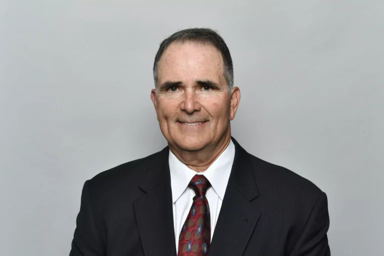 A man in a suit and tie, smiling confidently, appears ready to tackle any challenge, much like a strategic player among the Cowboys.