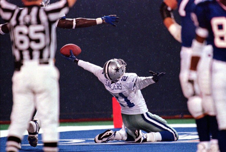 Football player kneeling and holding a football in the end zone as a referee signals a touchdown, envisioning himself as the next Cowboys coach.